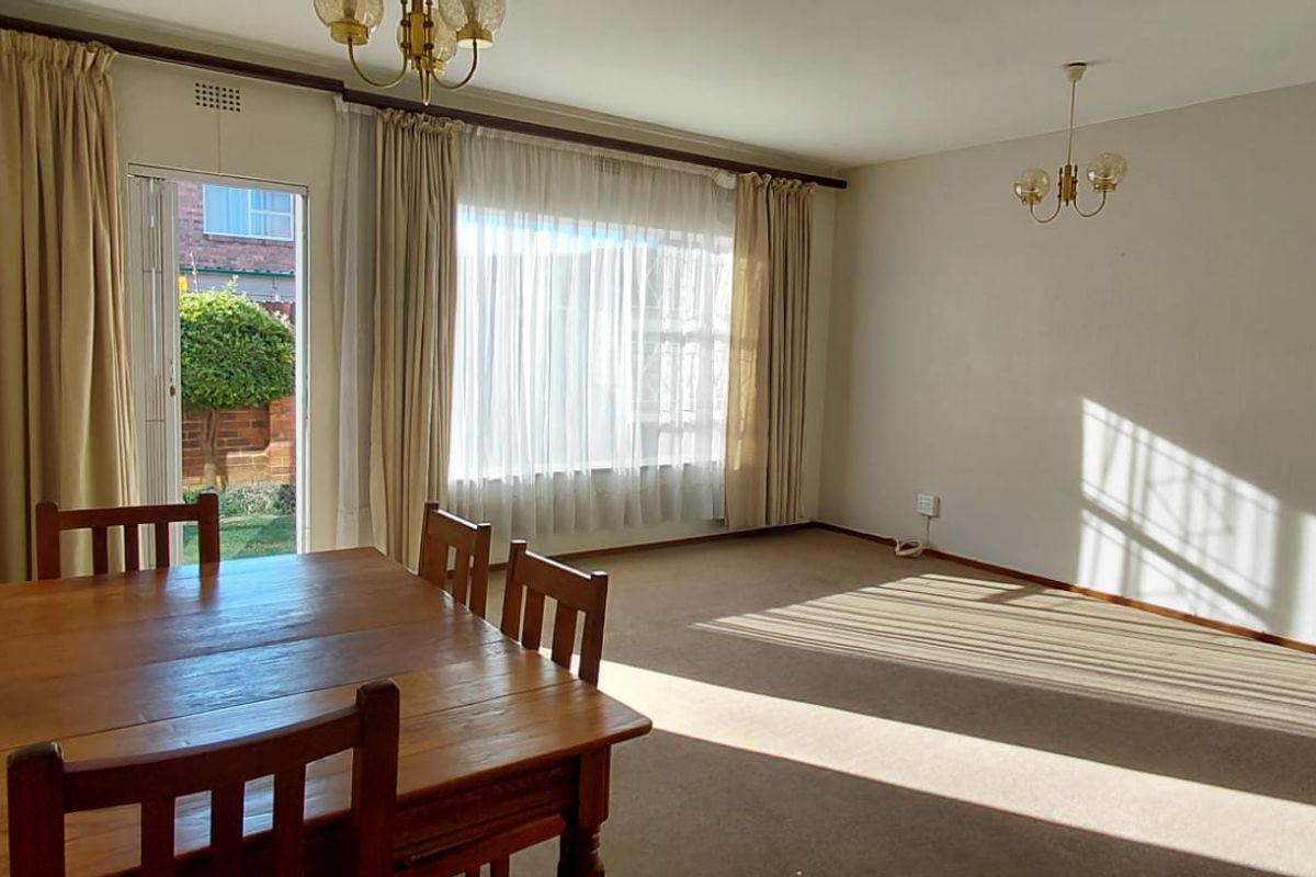Spacious living area featuring carpeted flooring, natural light through large windows, and direct access to an outdoor patio area.