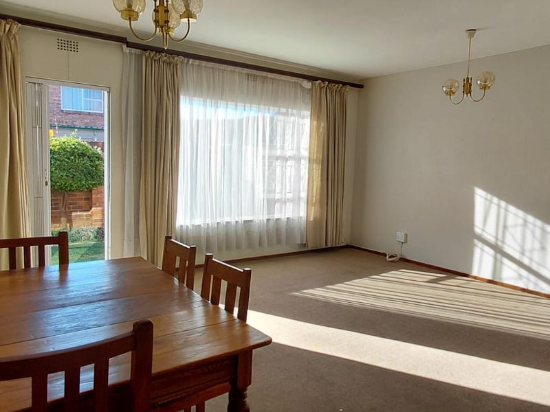 Spacious living area featuring carpeted flooring, natural light through large windows, and direct access to an outdoor patio area.