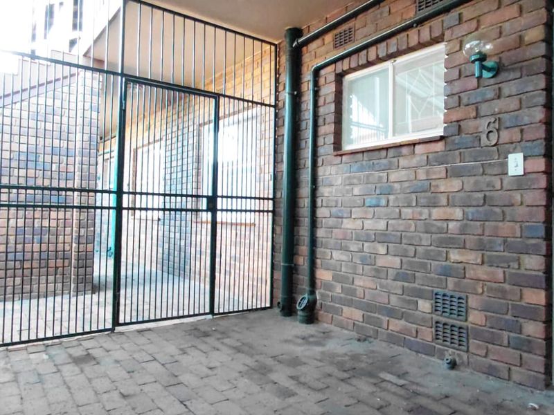 Private apartment entrance featuring a secure gated courtyard, brick facade, and security door access.