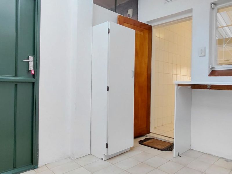 A functional laundry area featuring tiled flooring, plumbing connections for appliances, and a built-in storage cupboard.