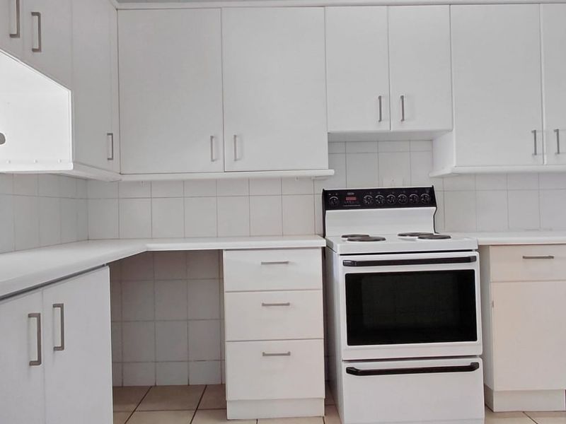 A clean, functional kitchen featuring white cabinetry, tiled backsplash, and a freestanding stove, offering a neutral canvas for potential updates.