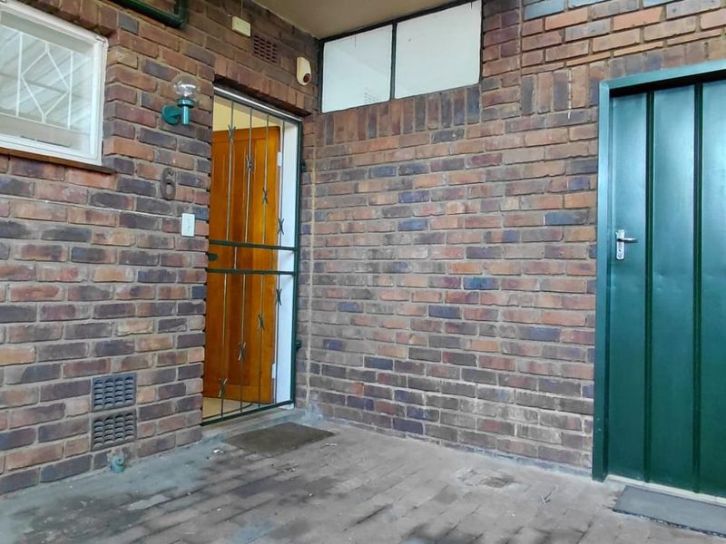 Entrance area featuring exposed brick walls, a security gate, and a metal door, providing a functional and secure access point to the apartment.