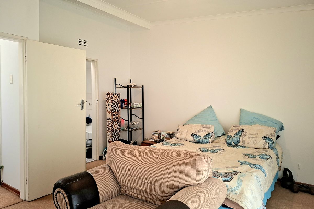 A standard bedroom featuring carpeted flooring, coving, and an adjoining doorway leading to an en-suite or bathroom area.