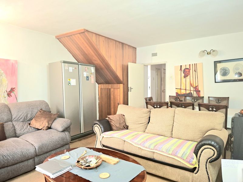 Open plan living and dining area featuring wood paneling detail and built-in storage space.