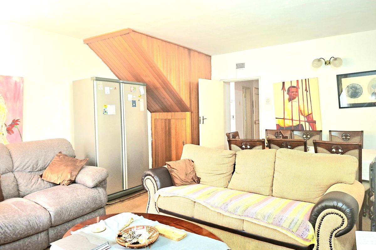 A living room area featuring timber wall paneling and access to an adjacent room, providing a functional space for relaxation.