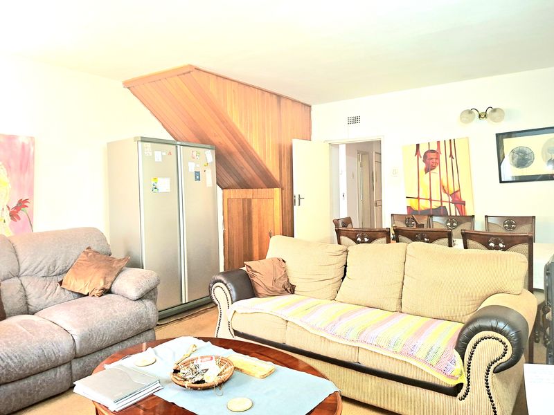 A living room area featuring timber wall paneling and access to an adjacent room, providing a functional space for relaxation.