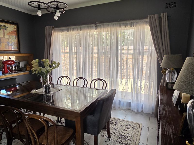 A well-maintained dining room featuring dark painted walls, tiled flooring, and a convenient pass-through window connecting to the kitchen area.