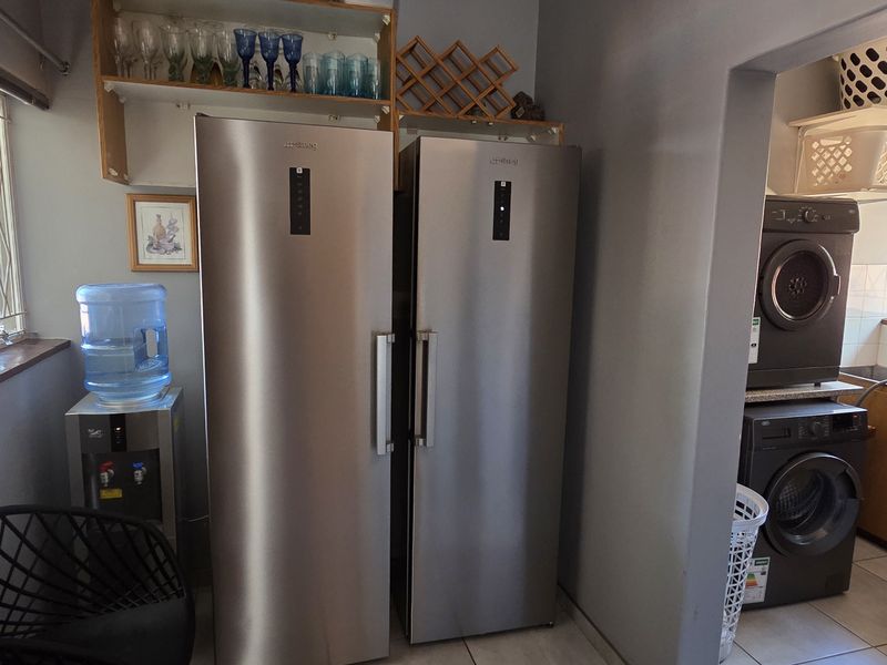 A functional scullery area featuring built-in cabinetry, a sink, and dedicated space for laundry appliances, providing practical utility and storage.