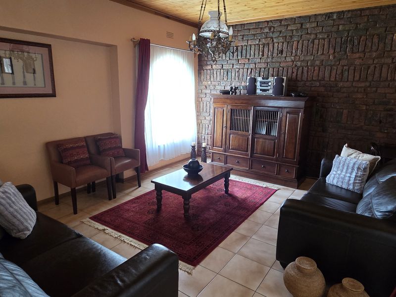 A cozy living room featuring an exposed brick feature wall, timber ceiling, and tiled flooring, creating a warm and traditional atmosphere.