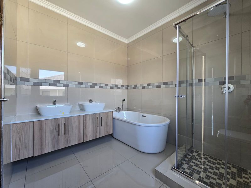 Modern bathroom featuring a double vanity, a sleek freestanding bathtub, and a separate glass-enclosed shower with contemporary wall and floor tiling.