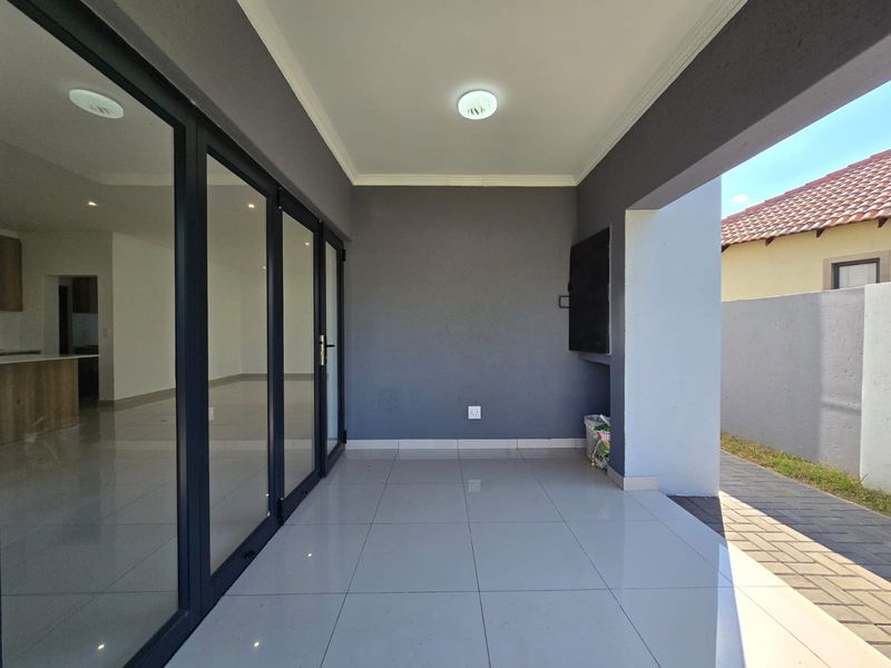 A modern covered patio featuring tiled flooring, recessed lighting, and large sliding glass doors, providing a seamless transition to the interior living space.