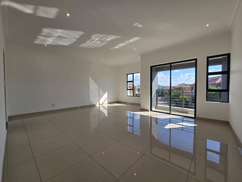 Spacious, sunlit living area featuring polished tile flooring, recessed lighting, and large sliding glass doors opening onto a private balcony.