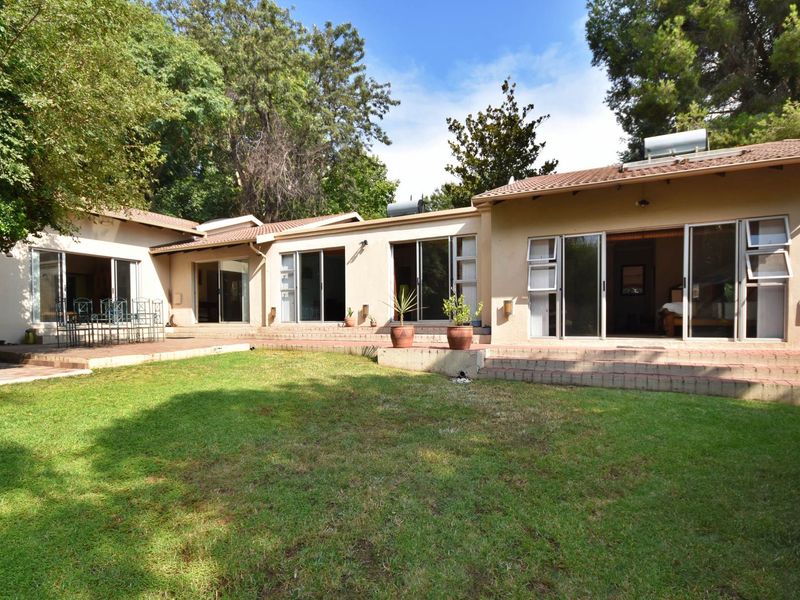 Rear view of the house featuring a spacious lawn, brick patio area, and multiple sliding glass doors providing access to the interior living spaces.