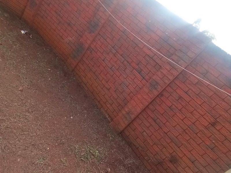 A private rear outdoor area featuring a high brick boundary wall and an installed washing line, currently requiring landscaping and maintenance.