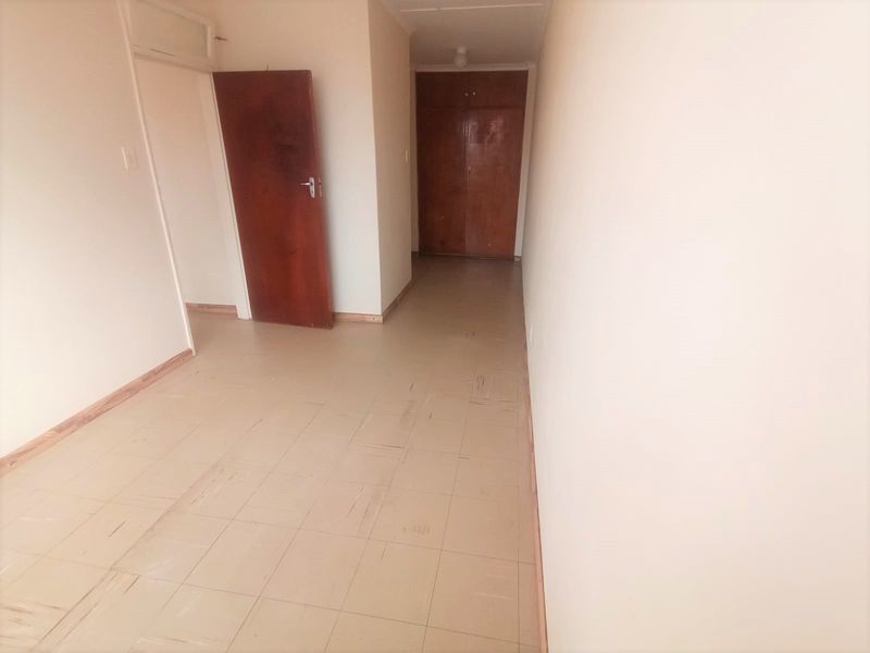 An empty bedroom featuring tiled flooring and built-in wooden cupboards, offering a blank canvas for renovation or interior design updates.