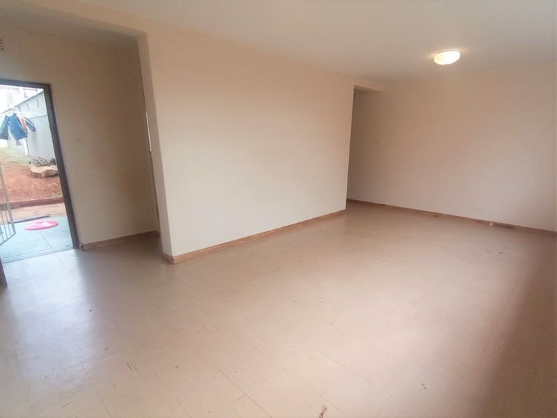 An empty, open-plan living area featuring neutral walls, tiled flooring, and direct access to an outdoor space.