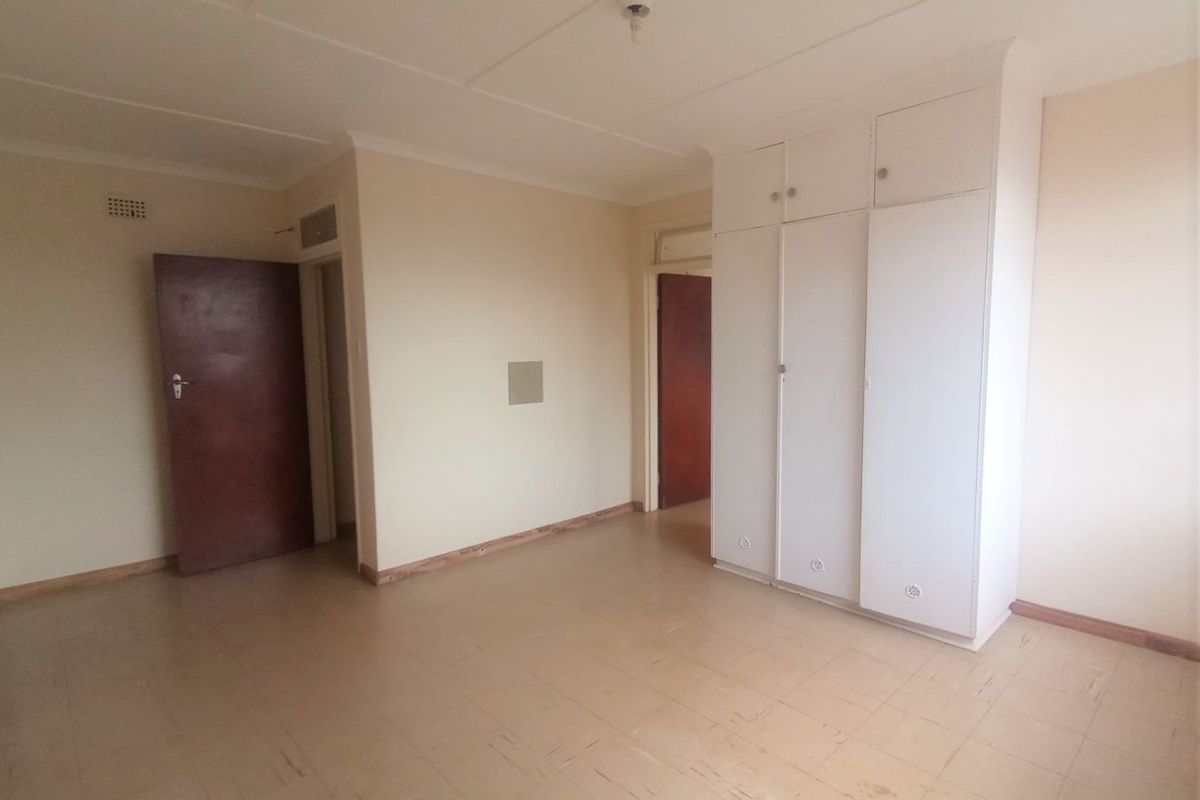 An empty bedroom featuring built-in cupboards, tiled flooring, and coved ceilings, offering a blank canvas for renovation or interior design updates.