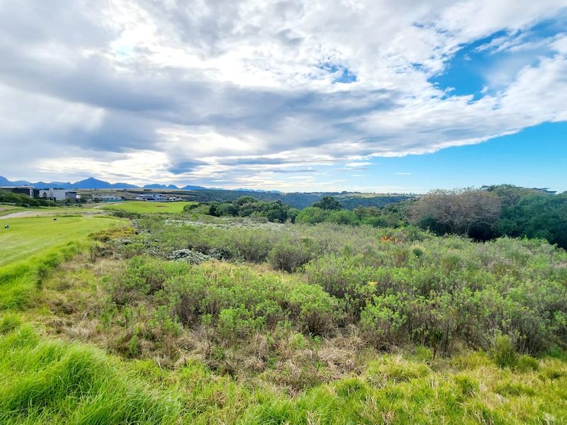 A scenic view overlooking a natural landscape and adjacent golf course fairway with distant mountain vistas.