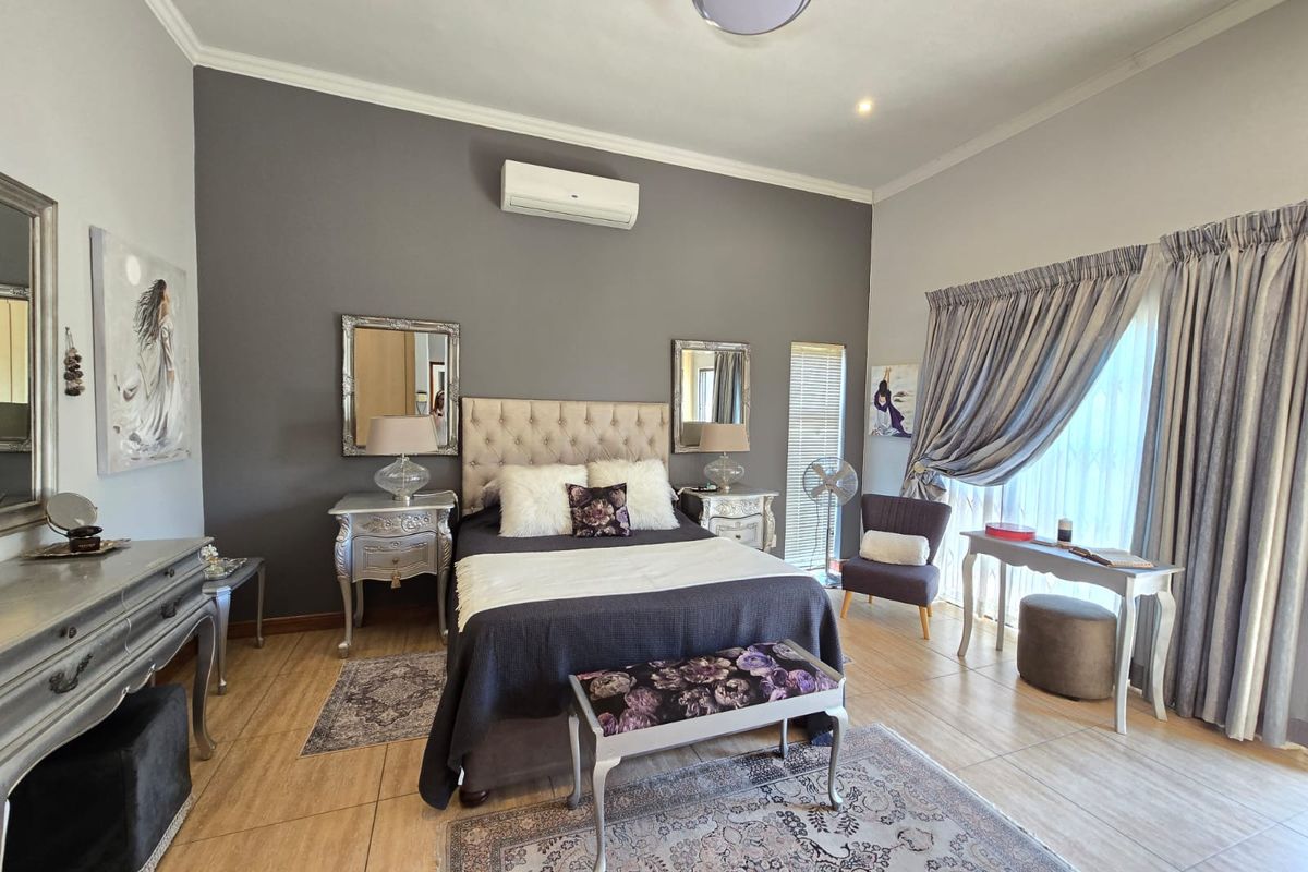 A well-maintained bedroom featuring tiled flooring, a split-system air conditioner, and a ceiling fan, with neutral wall tones and ample natural light.