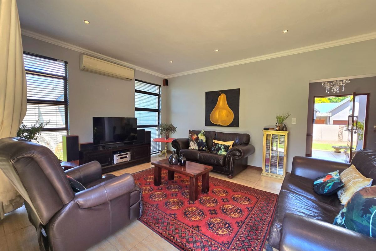 A comfortable living room featuring tiled flooring, recessed downlighting, and a wall-mounted split-system air conditioner, with direct access to an outdoor area.