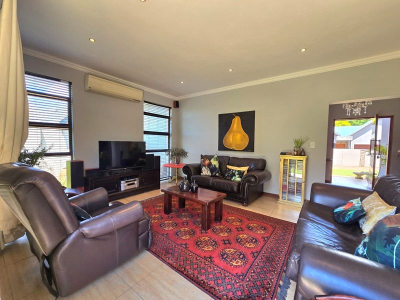 A comfortable living room featuring tiled flooring, recessed downlighting, and a wall-mounted split-system air conditioner, with direct access to an outdoor area.
