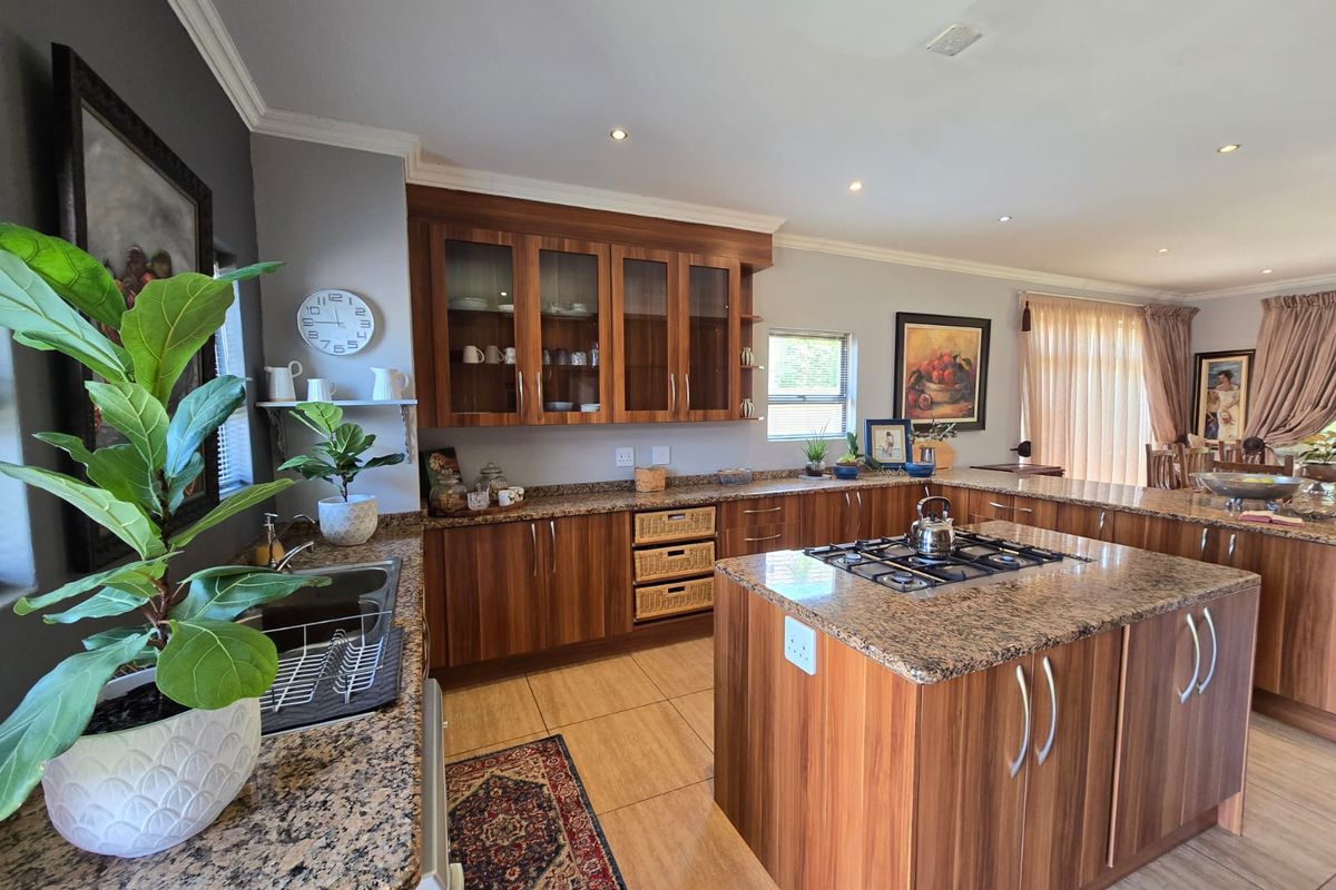 Spacious kitchen featuring wood veneer cabinetry, granite countertops, a central island with a gas hob, and recessed lighting.