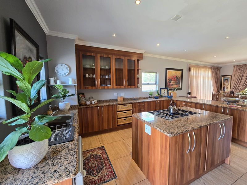 Spacious kitchen featuring wood veneer cabinetry, granite countertops, a central island with a gas hob, and recessed lighting.