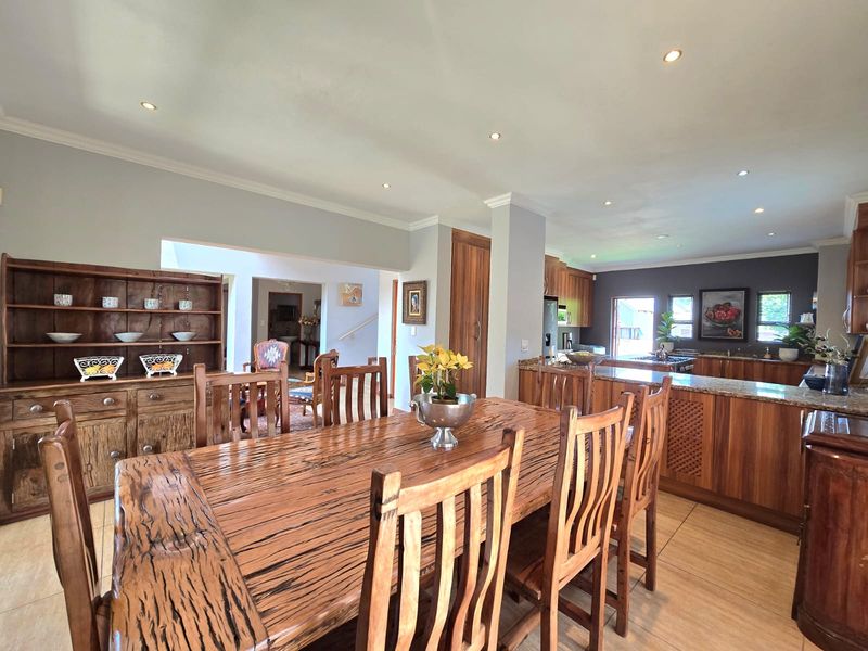 Spacious open-plan dining and kitchen area featuring warm wooden cabinetry, granite countertops, and recessed lighting, creating a functional and inviting living space.