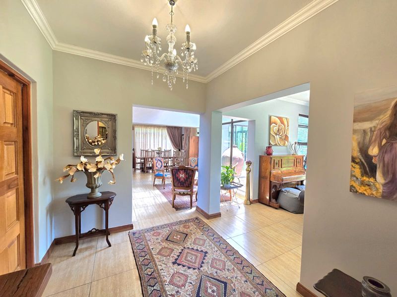 A bright and spacious living area featuring elegant crown molding, tiled flooring, and a classic chandelier, creating an inviting and open atmosphere.