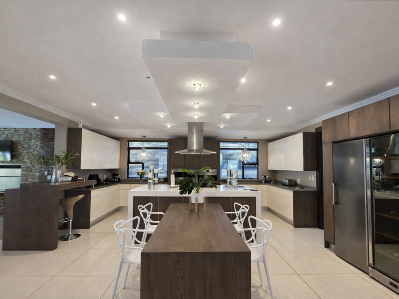 Spacious open-plan kitchen featuring a large central island, modern cabinetry, integrated appliances, and a striking stone feature wall in the adjacent living area.