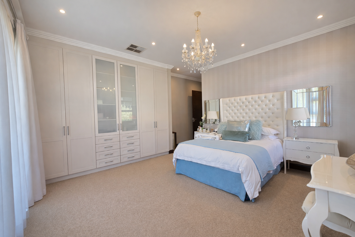 A well-appointed bedroom featuring extensive built-in cabinetry, neutral carpeting, crown molding, and recessed lighting, creating a polished and comfortable living space.