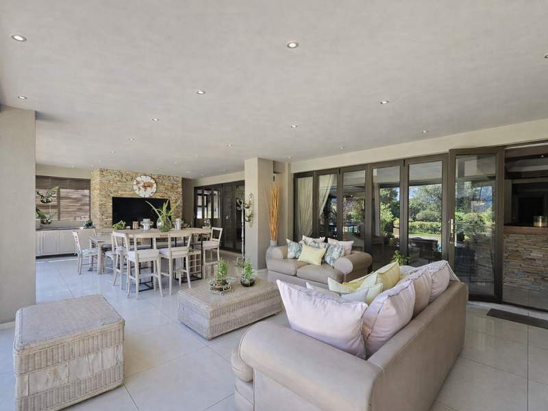 Spacious covered patio featuring a stone accent wall, recessed lighting, and large stacking glass doors that provide seamless indoor-outdoor flow.
