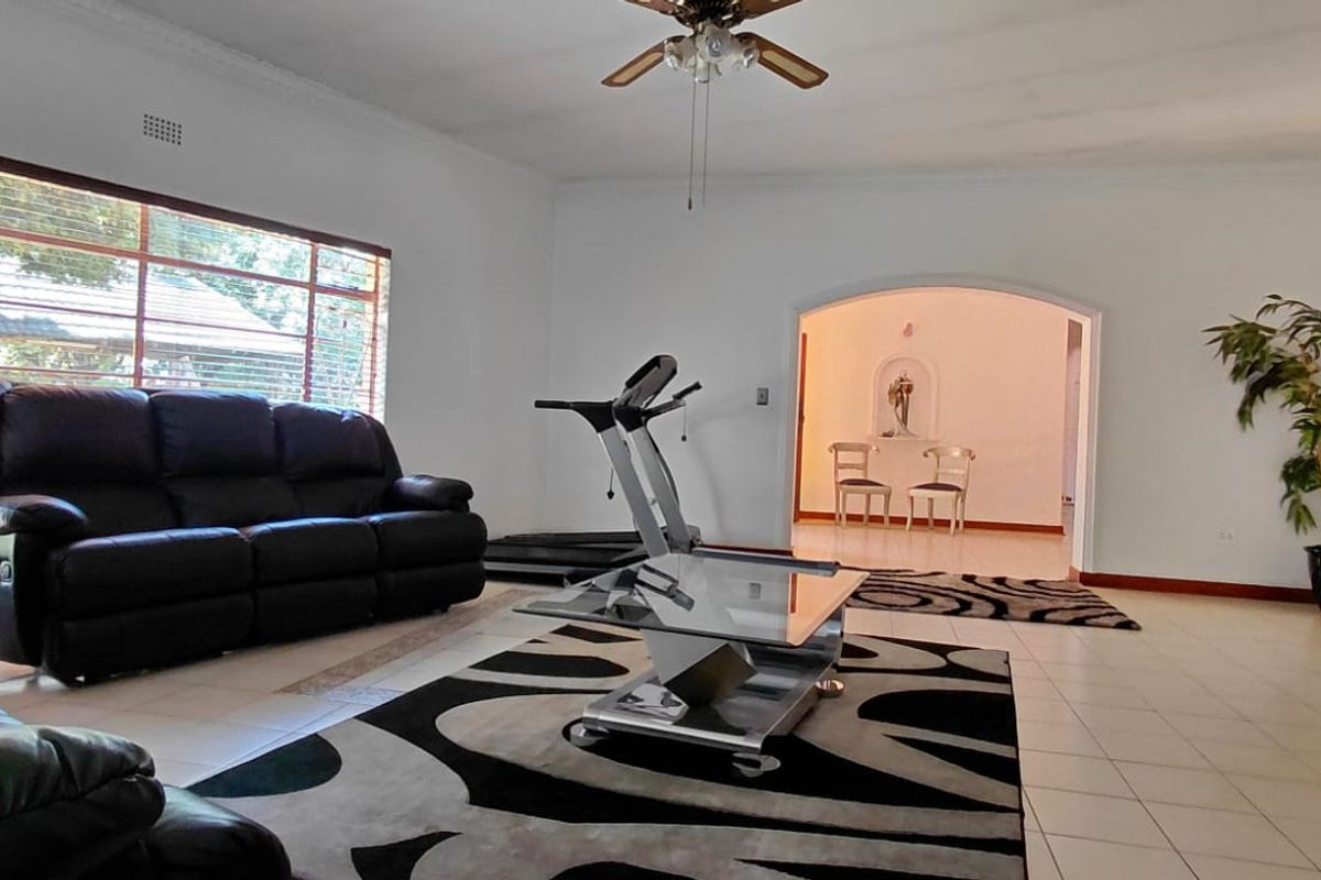 Spacious living room featuring large windows, tiled flooring, and an arched entryway leading to an adjacent room.