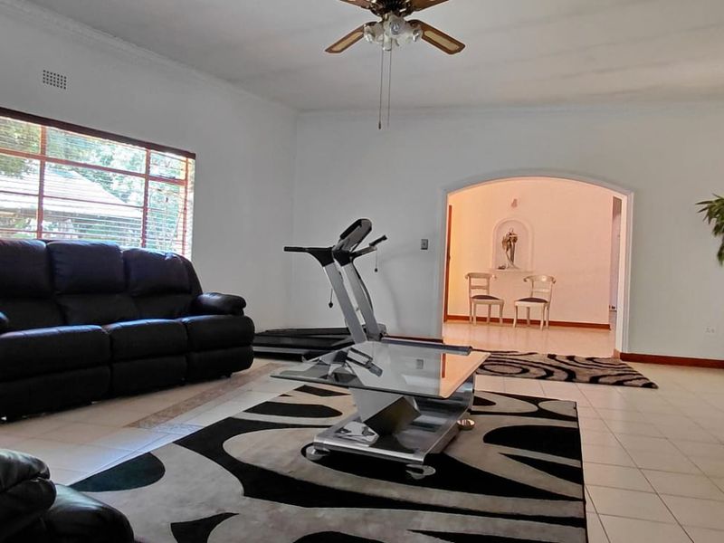 Spacious living room featuring large windows, tiled flooring, and an arched entryway leading to an adjacent room.