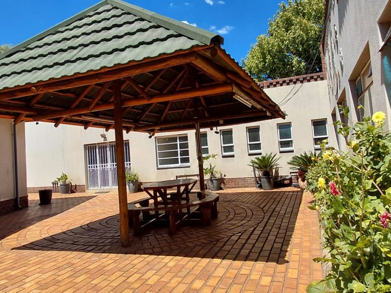 A paved outdoor patio area featuring a covered gazebo structure, providing a functional space for outdoor relaxation and entertainment.