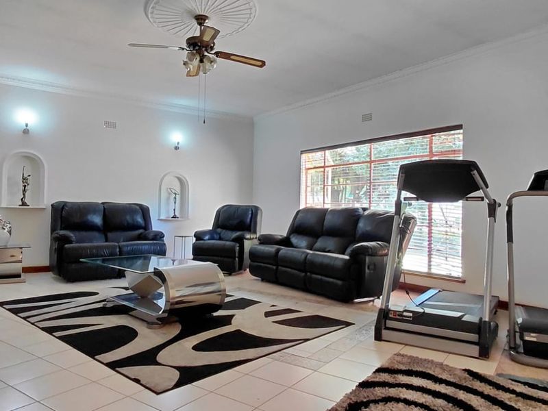 Spacious living room featuring tiled flooring, decorative ceiling rose with fan, and built-in wall niches, offering a versatile layout for relaxation.