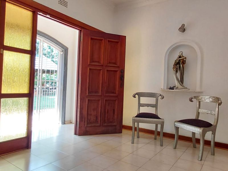 Entrance foyer featuring ceramic tile flooring, a decorative arched wall niche, and timber panelled doors leading to the exterior.