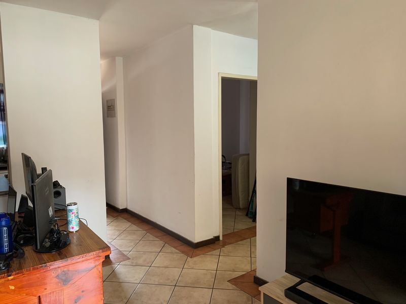 A functional hallway area featuring ceramic floor tiles and neutral wall finishes, providing access to adjacent rooms within the apartment.