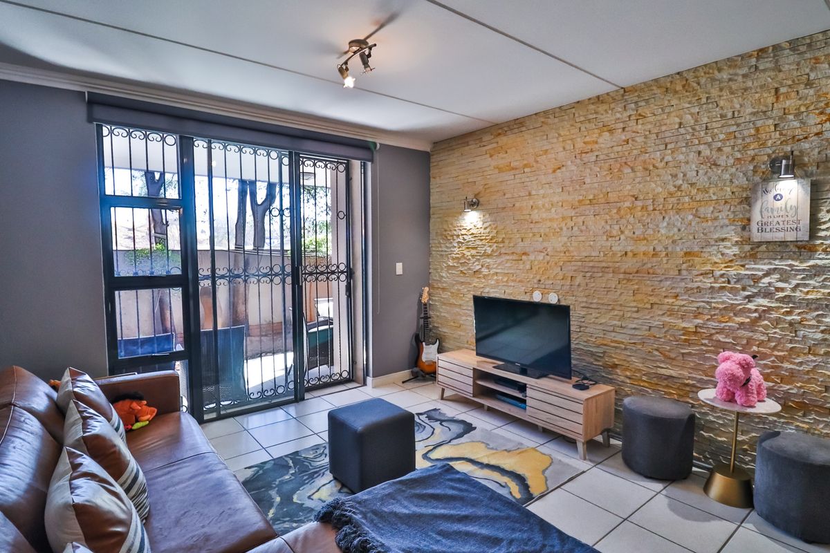 A comfortable living room featuring a textured stone accent wall, tiled flooring, and a sliding glass door providing access to an outdoor area.