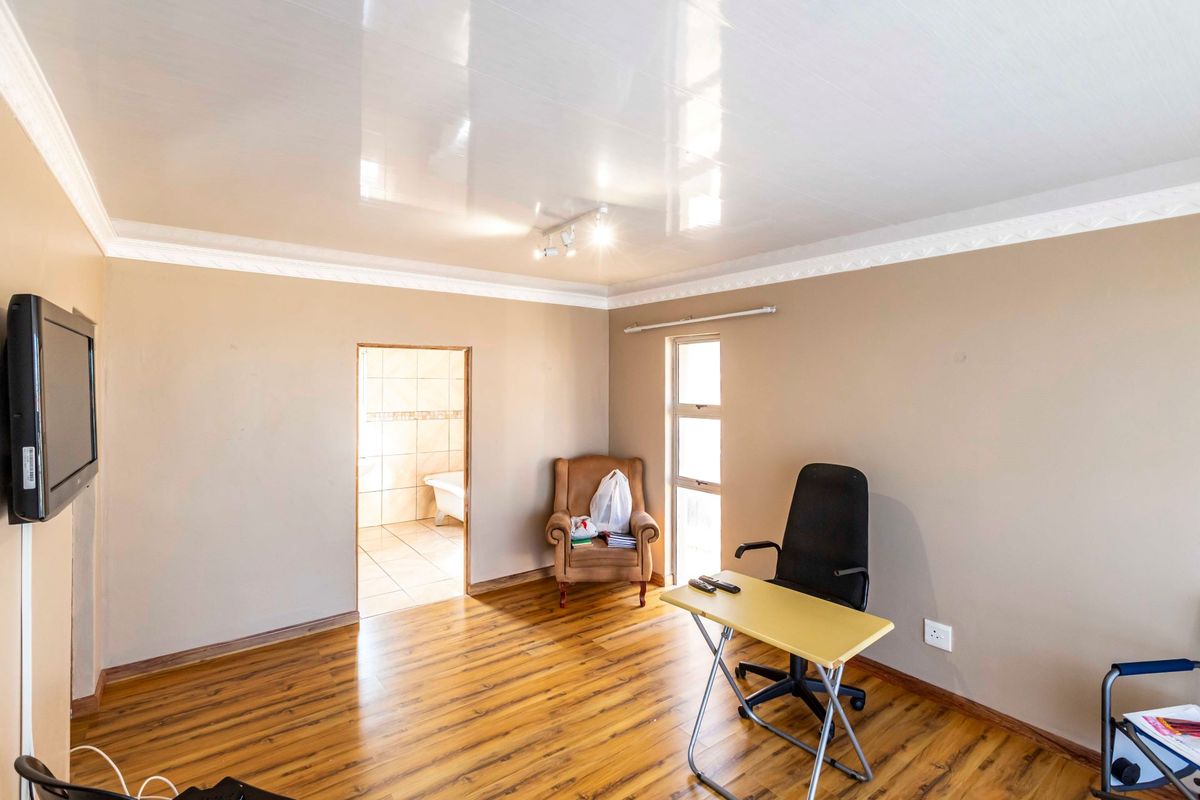 A bedroom featuring laminate flooring, a glossy ceiling with coving, and an adjoining en-suite bathroom.
