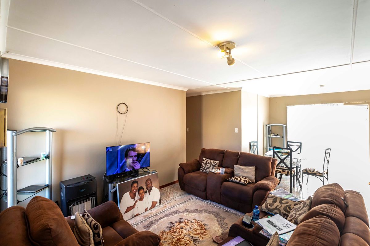 A functional living room area featuring tiled flooring and ceiling-mounted lighting, providing a comfortable space for relaxation and daily living.
