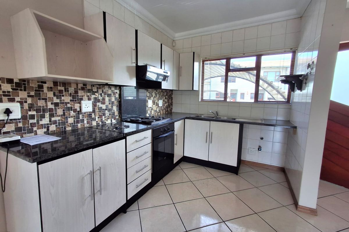 A clean, functional kitchen featuring light-toned cabinetry, granite countertops, a mosaic tile backsplash, and integrated appliances, offering a bright and well-maintained workspace.
