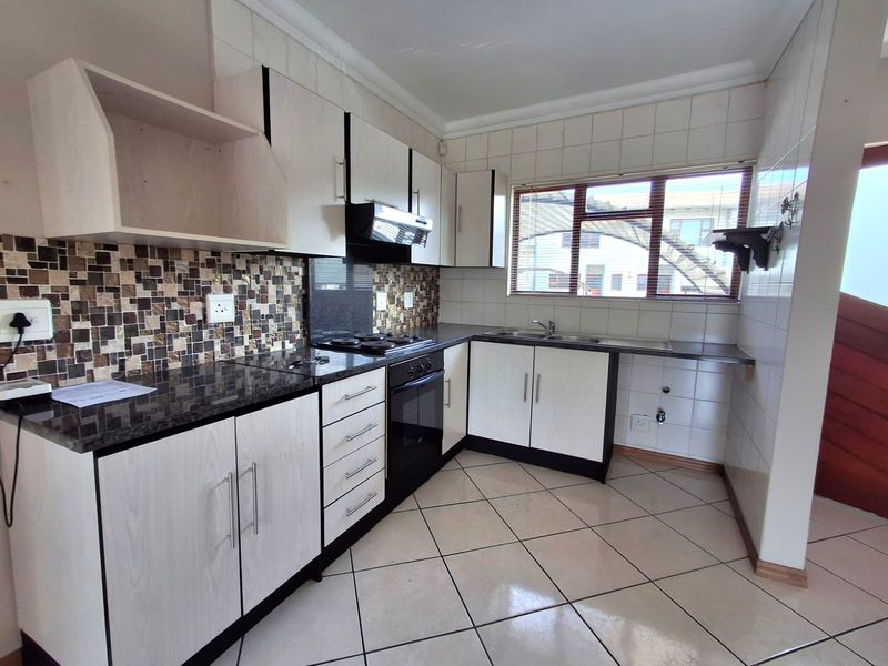 A clean, functional kitchen featuring light-toned cabinetry, granite countertops, a mosaic tile backsplash, and integrated appliances, offering a bright and well-maintained workspace.