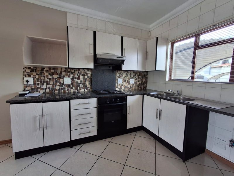 A functional kitchen featuring built-in cabinetry, granite countertops, a mosaic tile backsplash, and integrated appliances including an oven and gas hob.
