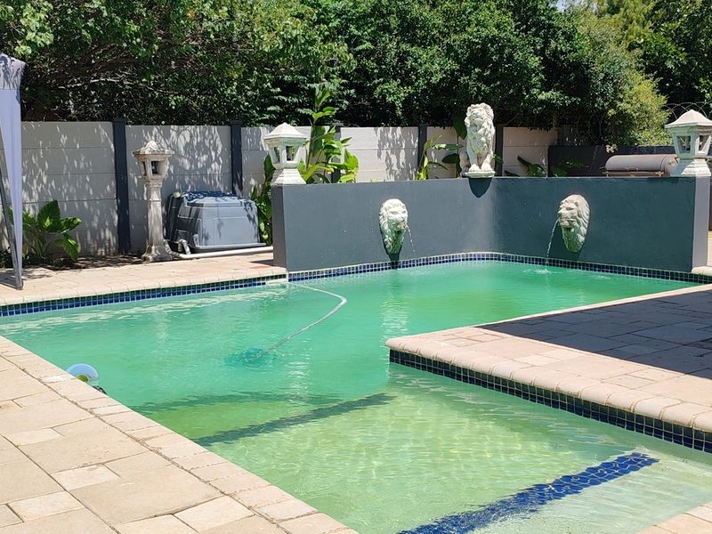Outdoor pool area featuring a paved patio, built-in water feature with lion head spouts, and perimeter boundary walling.