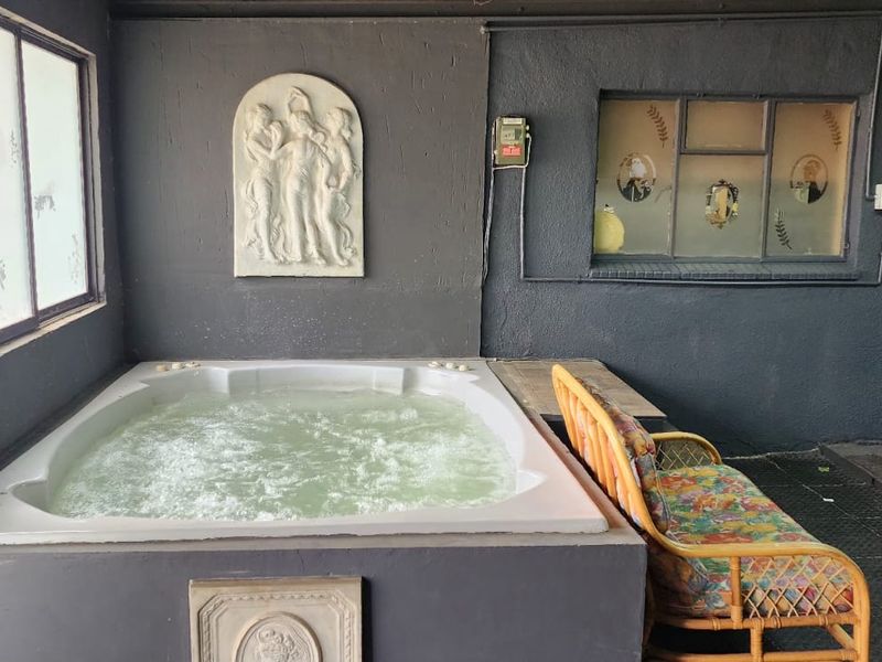 Indoor area featuring a built-in jacuzzi, dark textured walls, and tiled flooring, offering a private relaxation space.