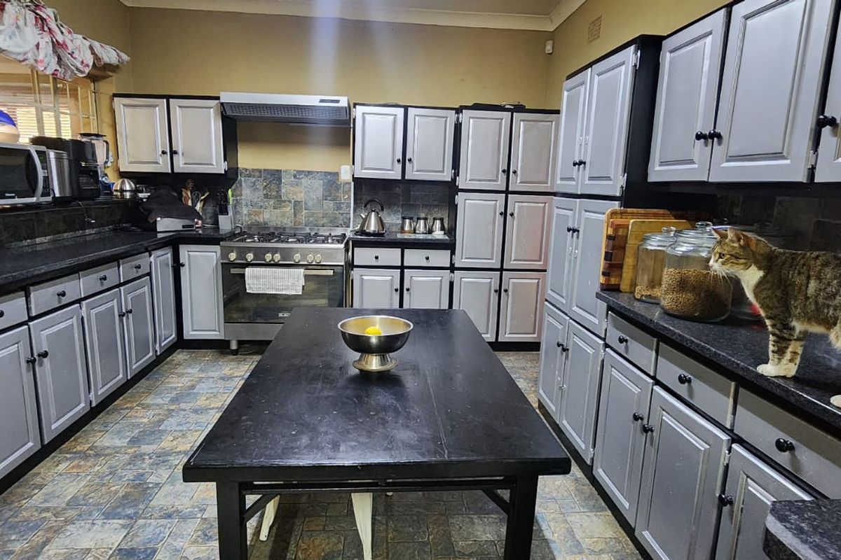 Spacious kitchen featuring extensive built-in cabinetry, a gas stove with extractor fan, stone tile backsplash, and durable laminate countertops.
