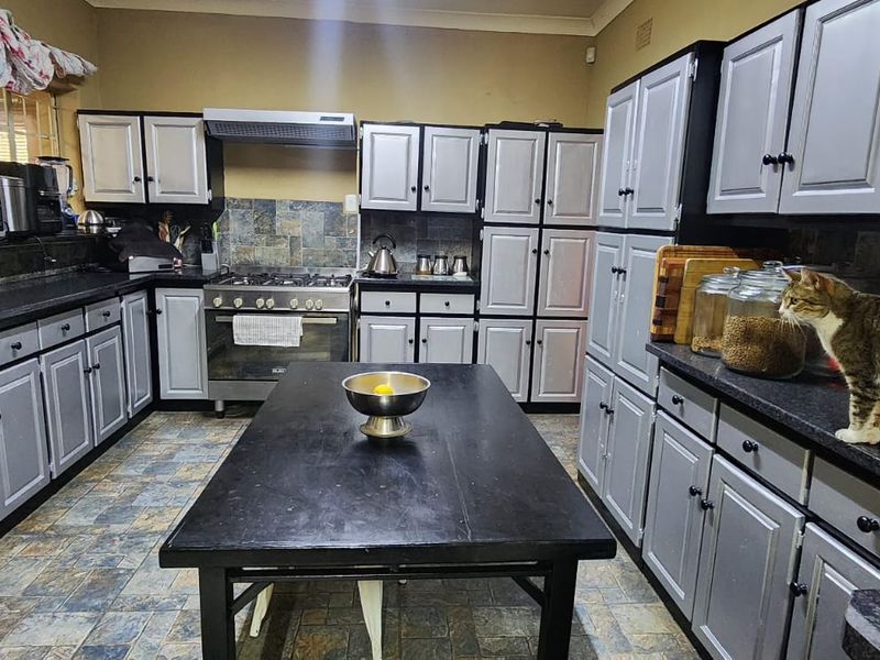 Spacious kitchen featuring extensive built-in cabinetry, a gas stove with extractor fan, stone tile backsplash, and durable laminate countertops.