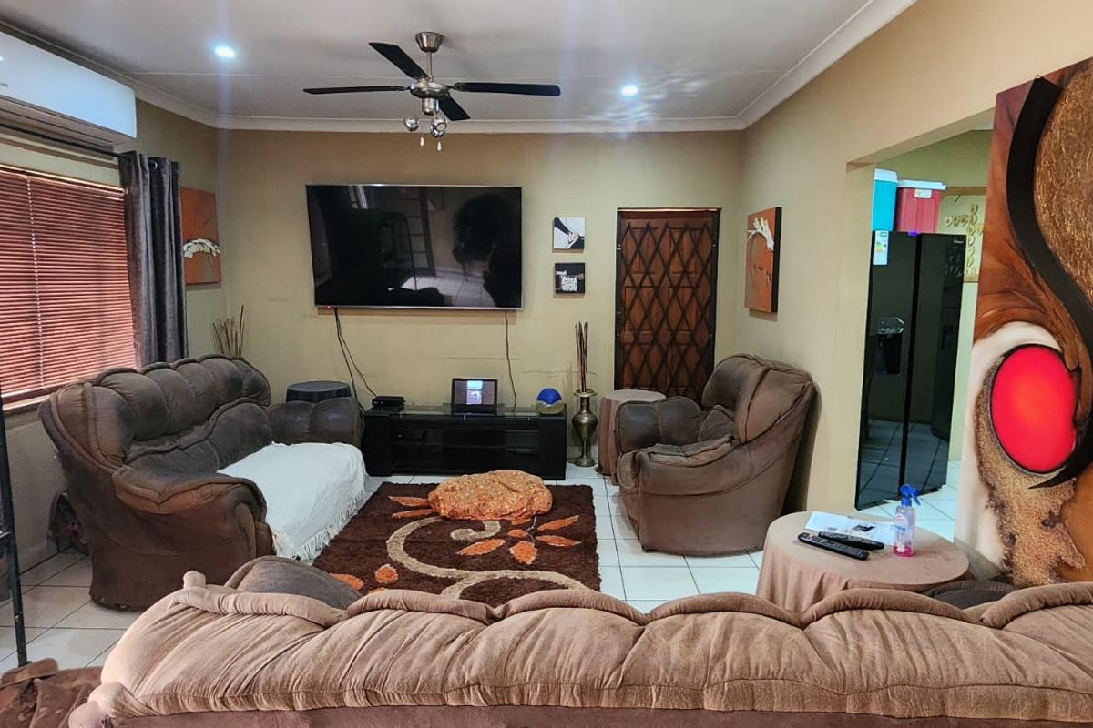 A comfortable living room featuring tiled flooring, a ceiling fan, and a wall-mounted air conditioning unit.