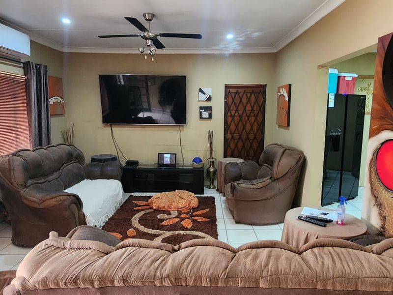 A comfortable living room featuring tiled flooring, a ceiling fan, and a wall-mounted air conditioning unit.